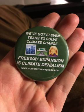 Image Shows one of our new buttons, with the text "We've got eleven years to solve climate change; freeway expansion is climate denialism"